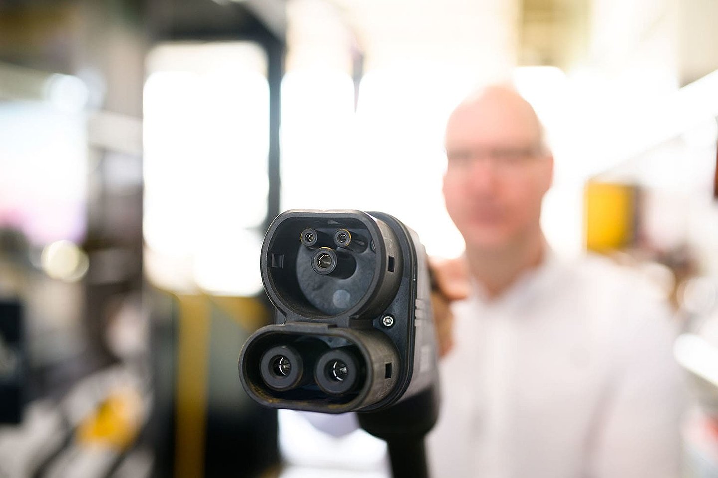eine Person hält das Ladekabel seines Busses in die Kamera