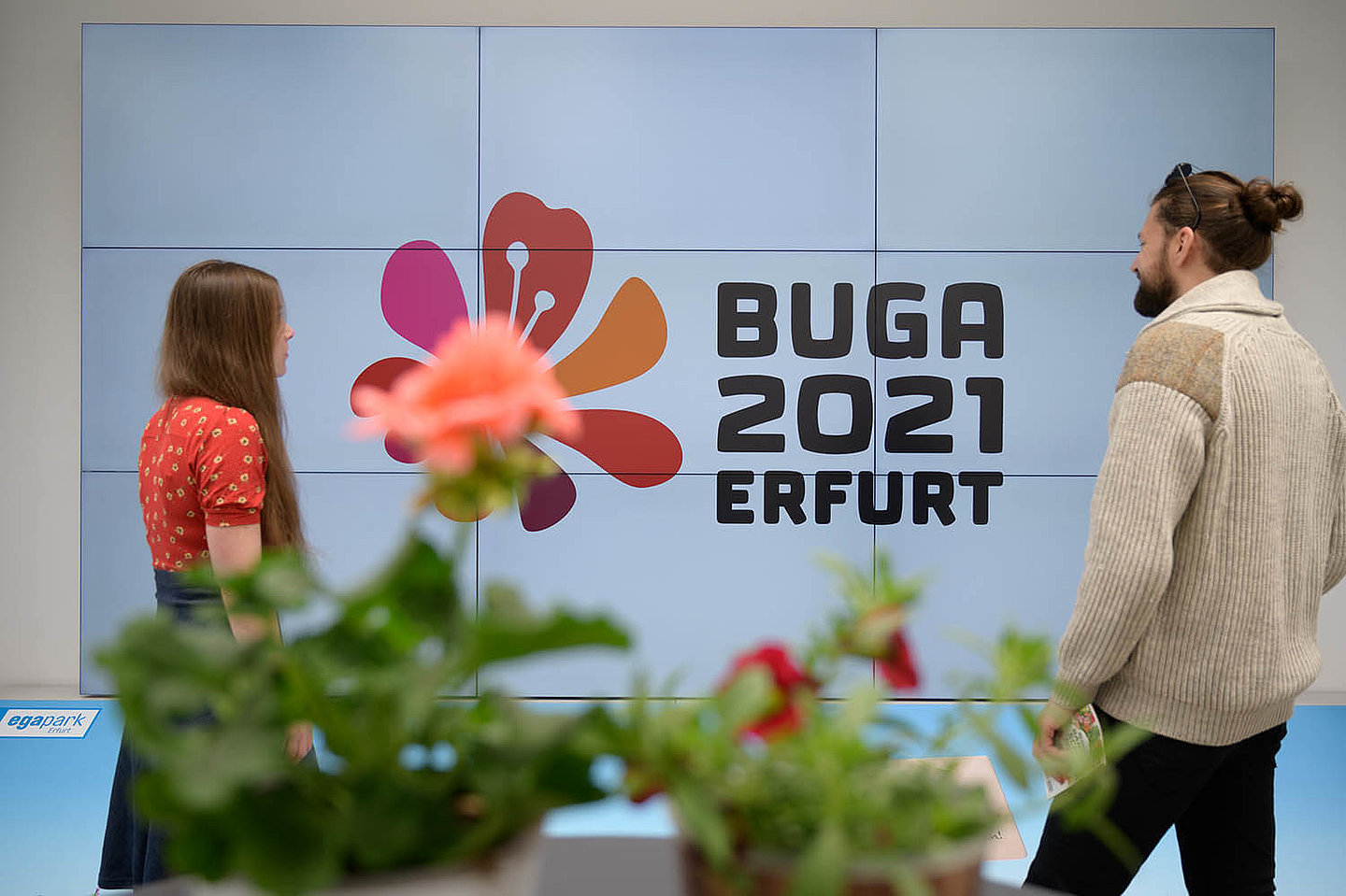 Zwei Personen welche sich das Logo der BUGA 2021 in Erfurt ansehen
