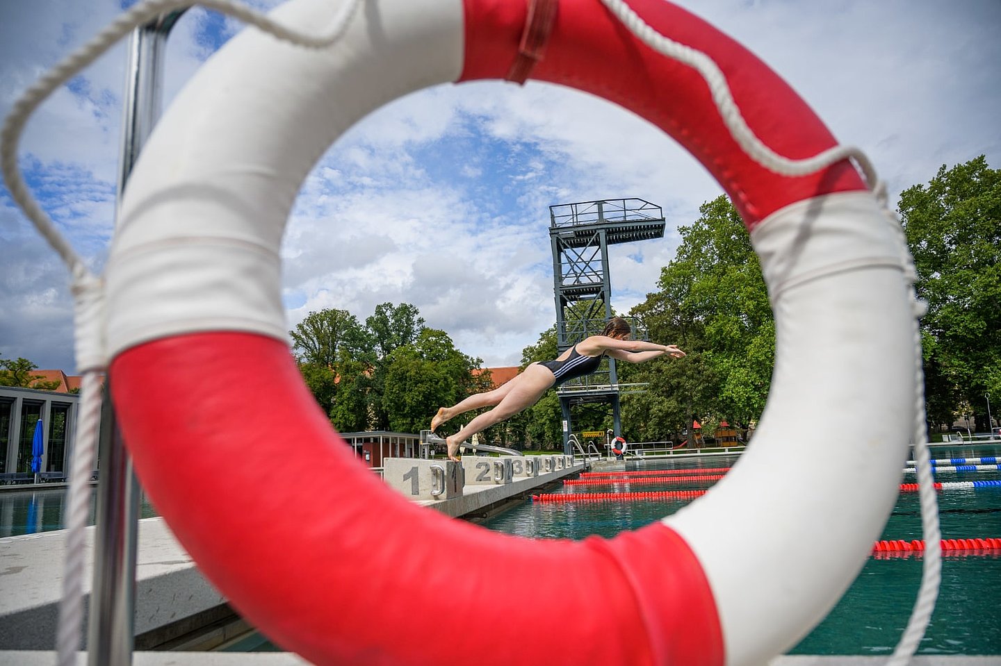 Schwimmerin Kopfsprung durch Schwimmreif fotografiert.