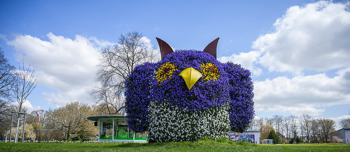 Eulenfigur aus Blumen. Im Hintergrund der Egapark