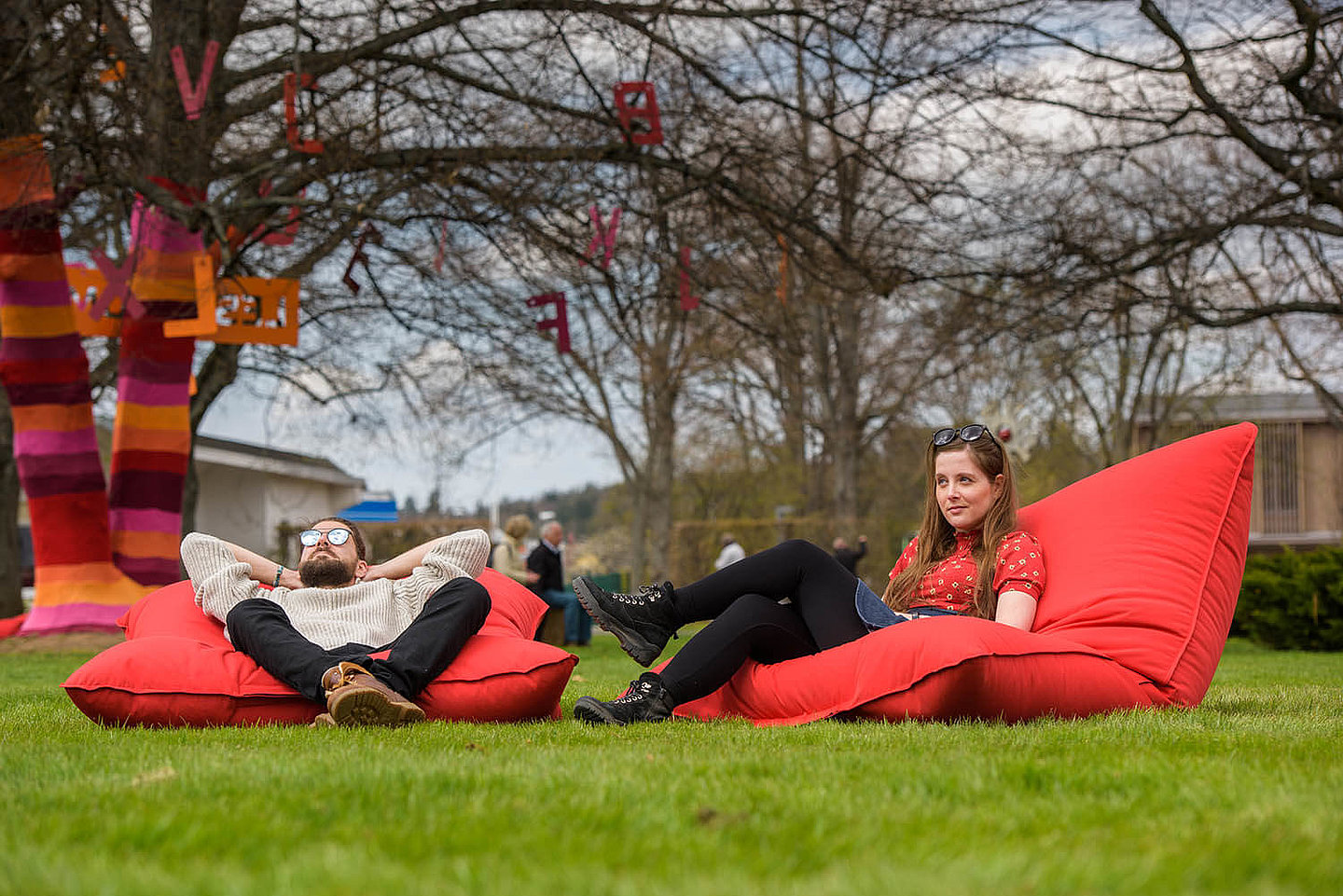 Zwei Personen, welche in Sitzsäcken unter Bäumen auf einer Wiese sitzen