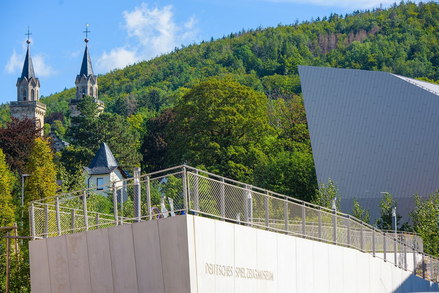 Neues Spielzeugmuseum mit Rampe und Kirchtürmen im Hintergrund