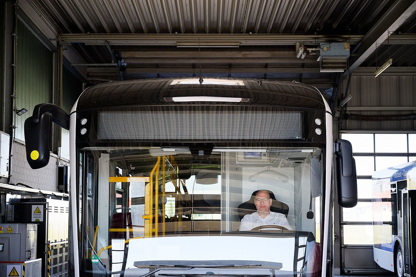 ein Busfahrer sitzt in seinem in der Garage stehenden Bus