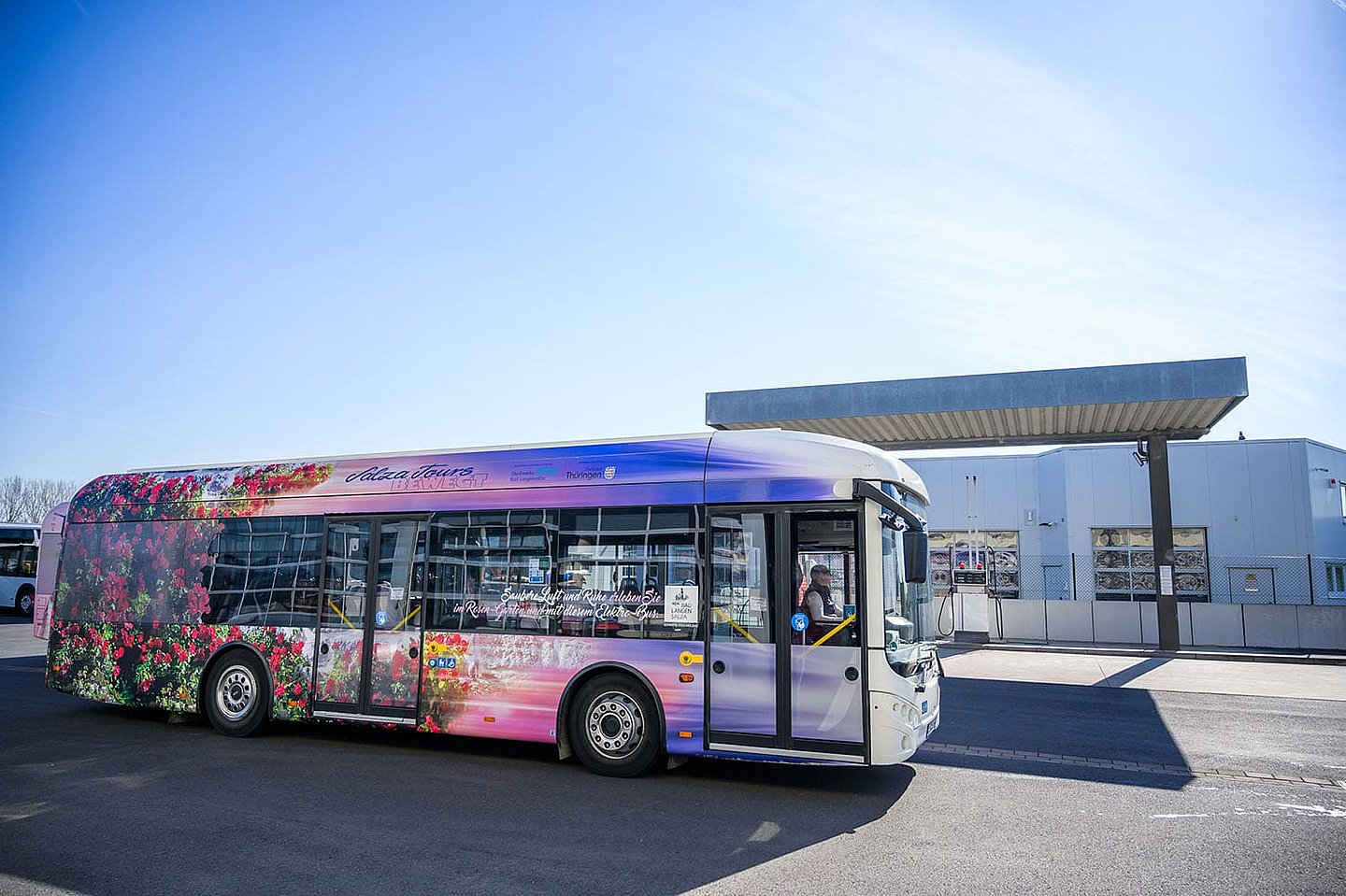 ein mit Blumen bedruckter Tourbus steht an einer Tankstelle