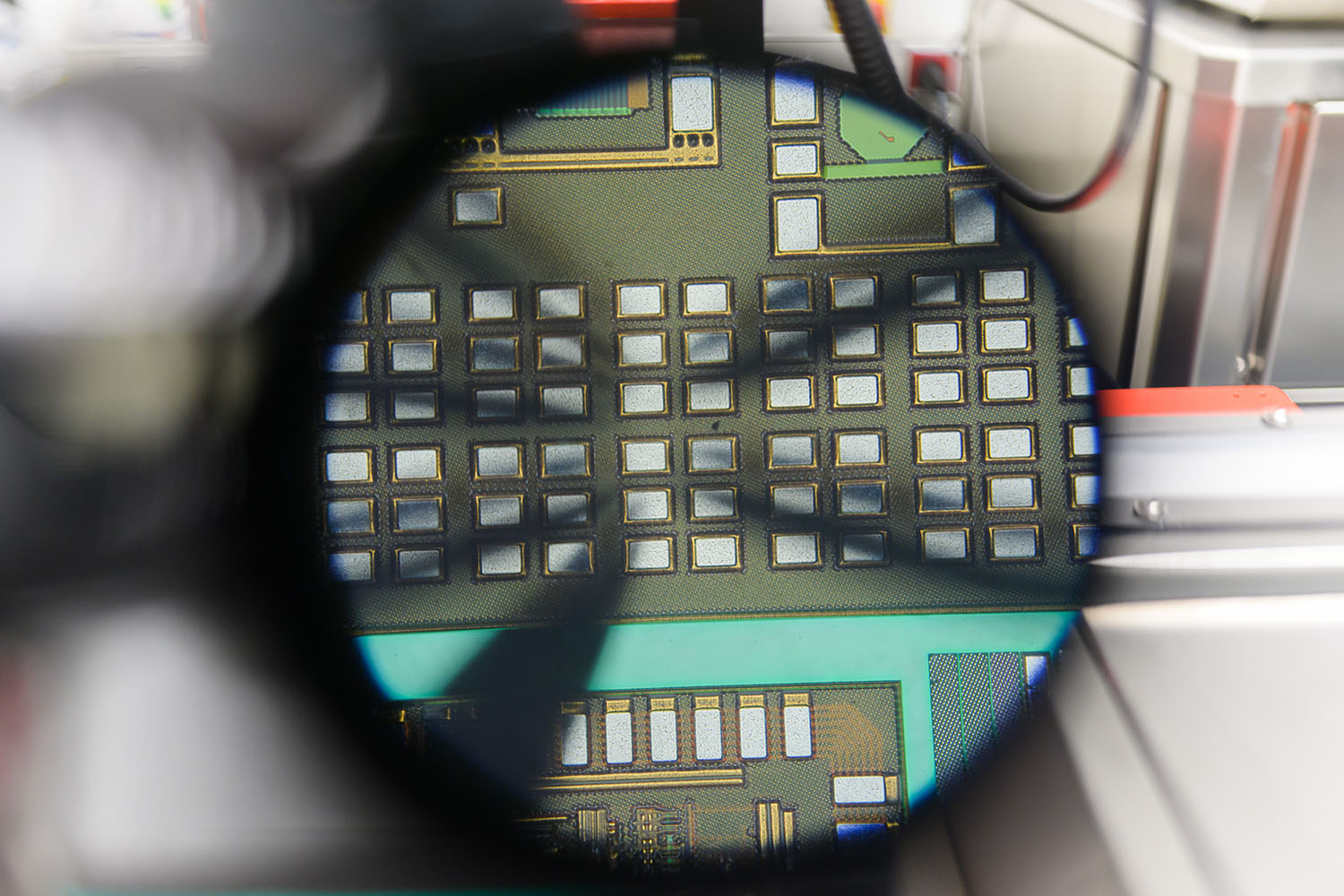 Blick durch das Okular eines Mikroskopes auf ein technisches Bauteil.